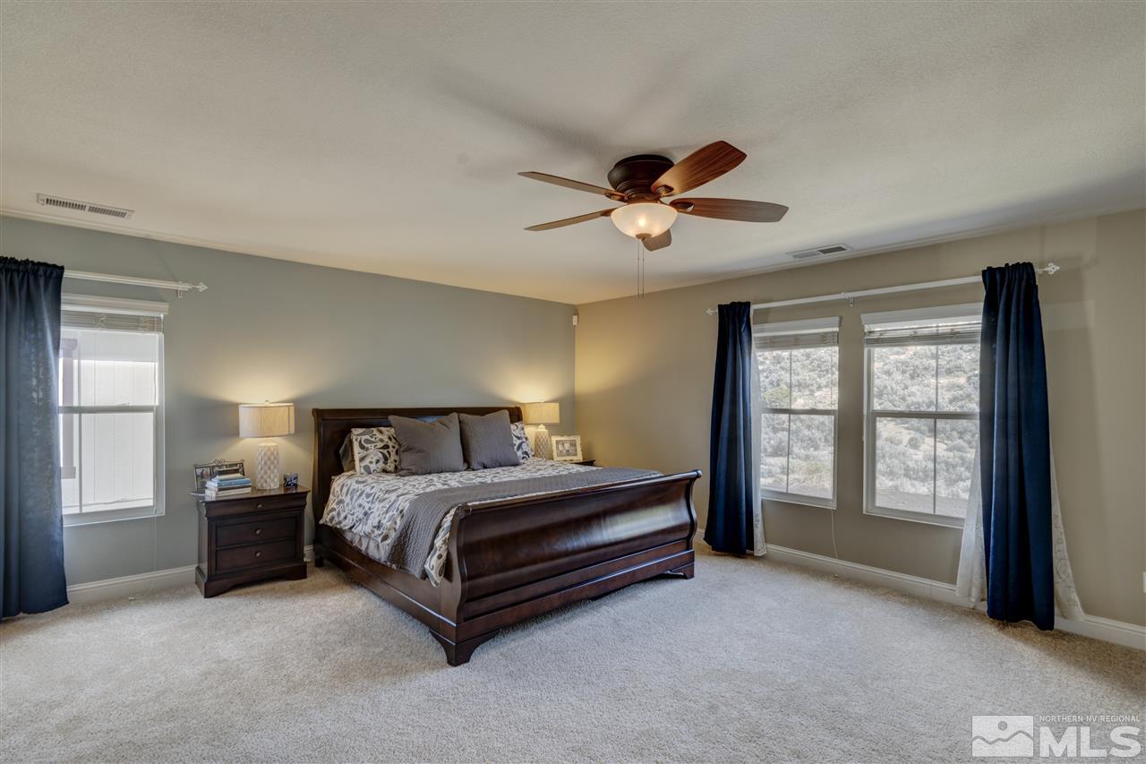 7638 Corso Street Reno, NV 89506 - Photo 14 of 29 a spacious bedroom with a bed and a ceiling fan in it