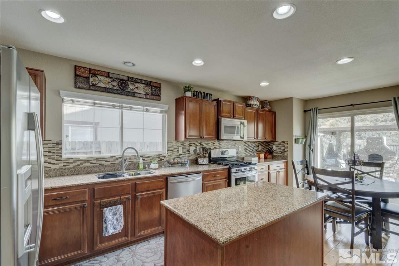7638 Corso Street Reno, NV 89506 - Photo 6 of 29 a kitchen with stainless steel appliances granite countertop a stove top oven a sink a dining table and chairs