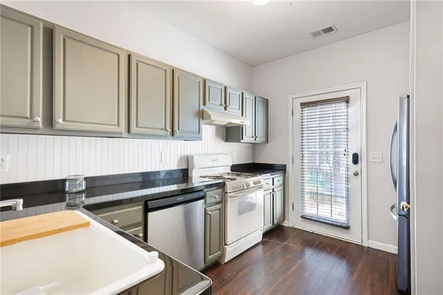 a kitchen filled with stainless steel appliances granite countertop a stove a sink and a refrigerator