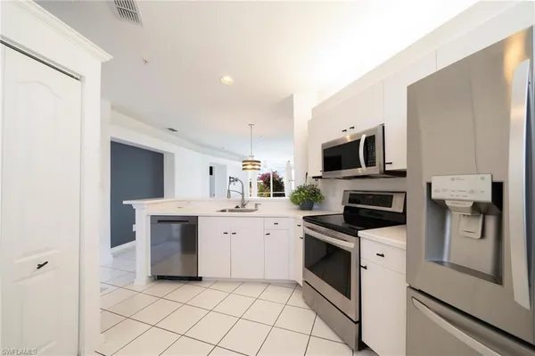 a kitchen with white cabinets and appliances