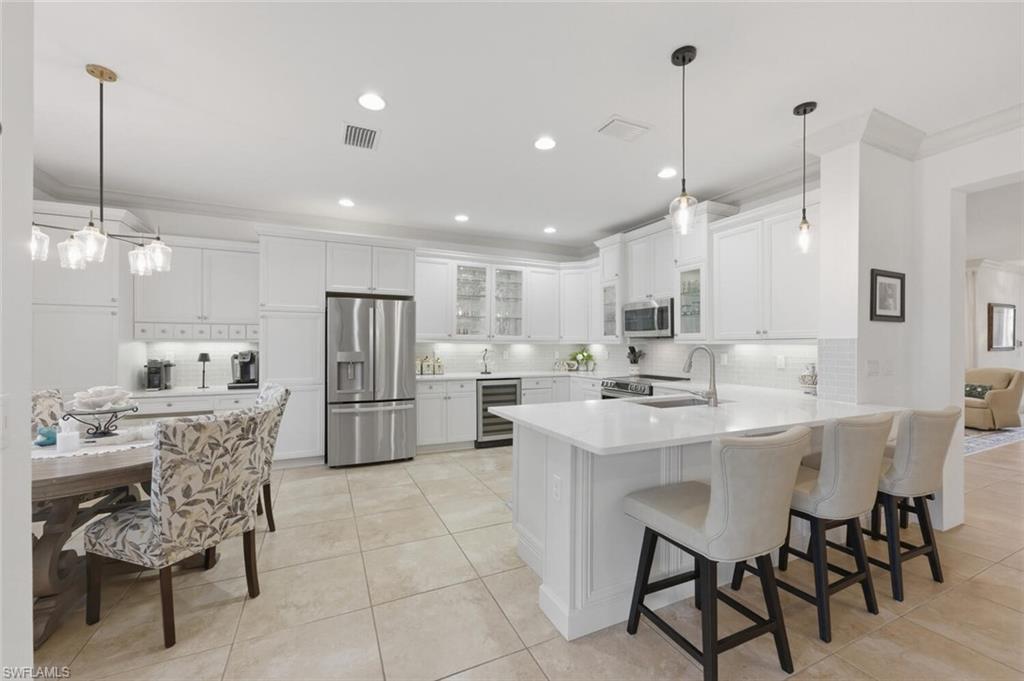 3306 Baltic Drive Naples, FL 34119 - Photo 14 of 49 a kitchen with stainless steel appliances kitchen island granite countertop a dining table chairs and white cabinets
