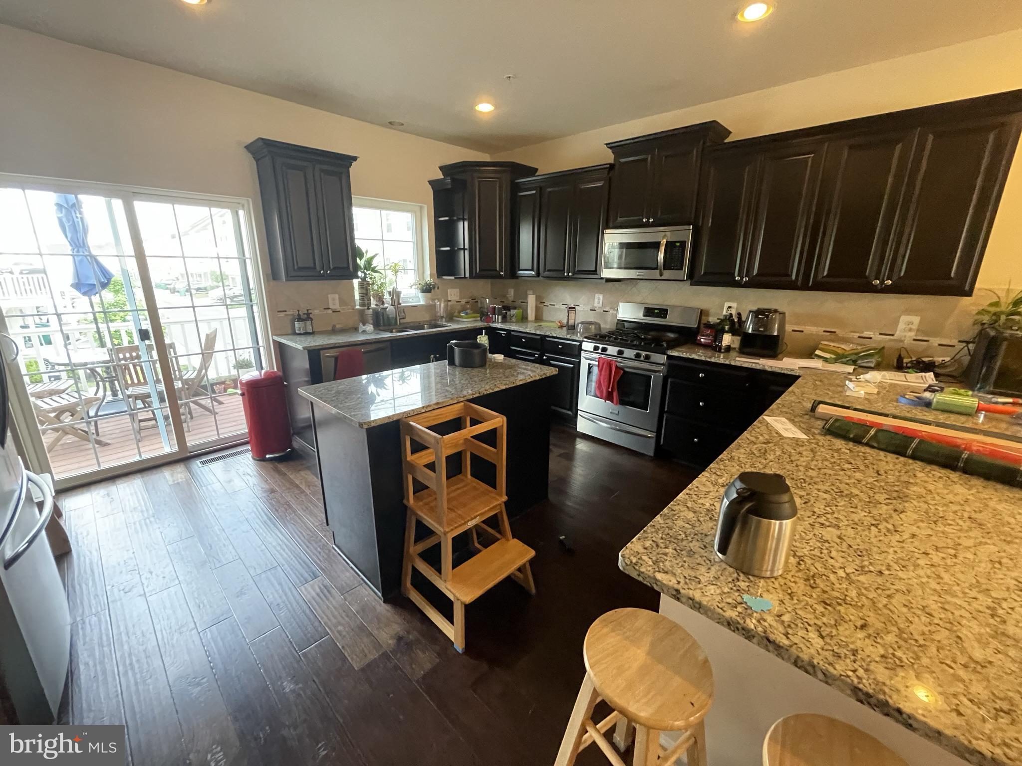 7563 Crowley Street Hanover, MD 21076 - Photo 4 of 15 a kitchen with granite countertop a stove top oven a sink dishwasher a dining table and chairs with wooden floor
