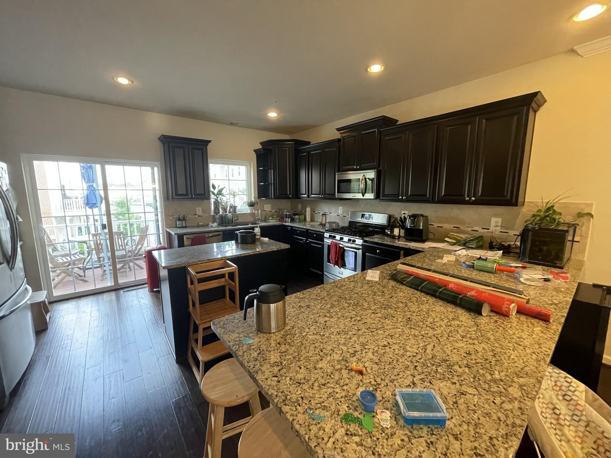 7563 Crowley Street Hanover, MD 21076 - Photo 6 of 15 an open kitchen with kitchen island wooden cabinets and stainless steel appliances