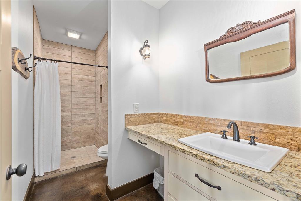11253 County Road 525 May, TX 76857 - Photo 25 of 40 a bathroom with a granite countertop sink a mirror and shower