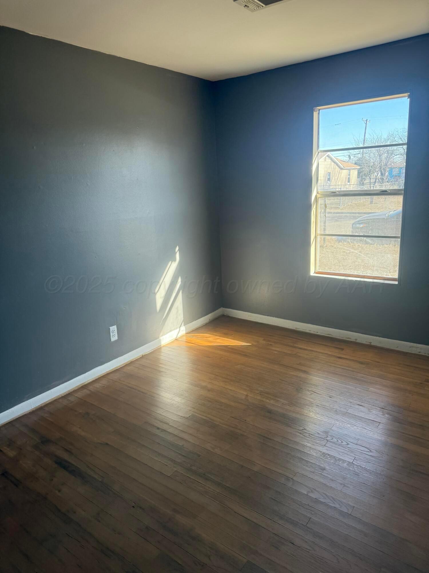 1211 North Apache Street Amarillo, TX 79107 - Photo 4 of 10 an empty room with wooden floor and windows