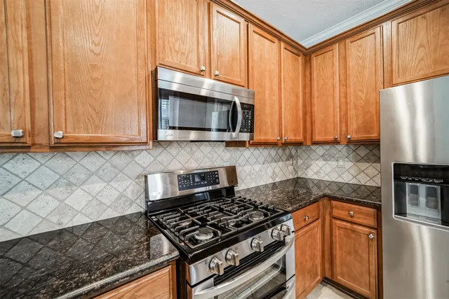 a kitchen with granite countertop a stove top oven cabinetry a sink and a window