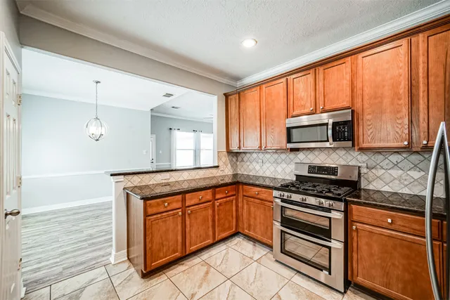 a kitchen with granite countertop a stove top oven microwave and cabinets