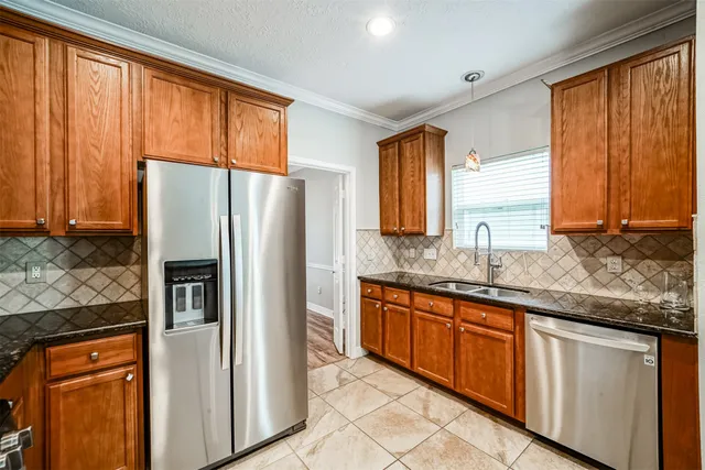 a kitchen with granite countertop stainless steel appliances a refrigerator cabinets and large window
