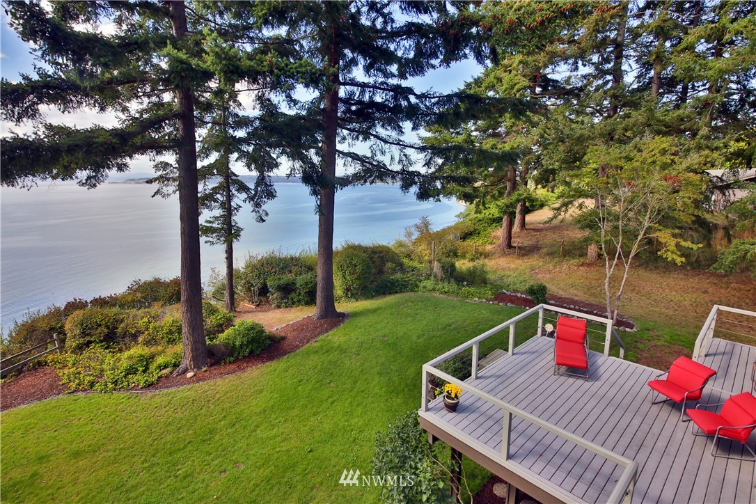 6924 Sills Road Clinton, WA 98236 - Photo 12 of 25 a view of a deck with a table and chairs under an umbrella