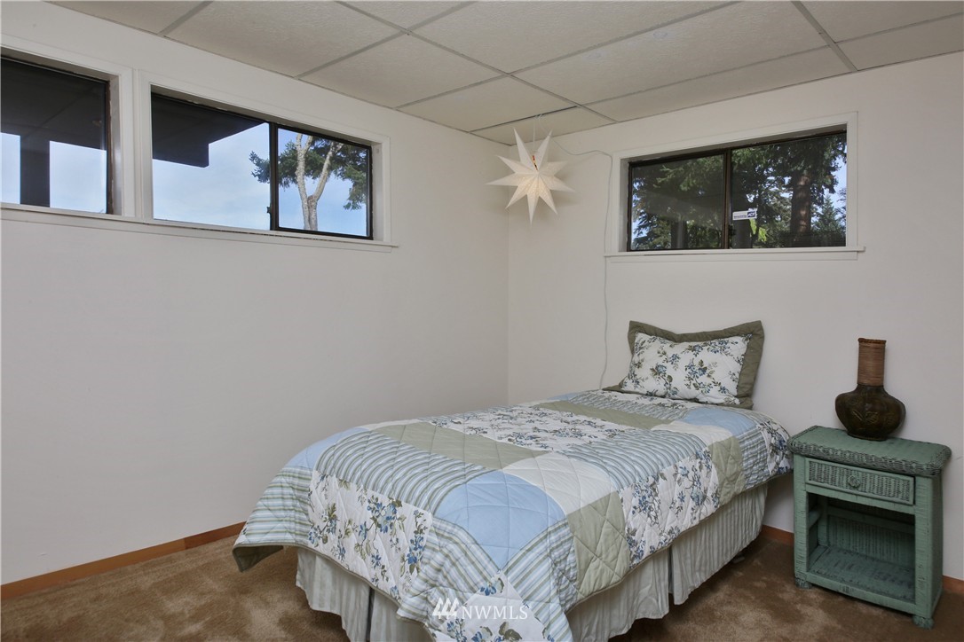 6924 Sills Road Clinton, WA 98236 - Photo 24 of 25 a bedroom with a bed a painting on the wall and a potted plant