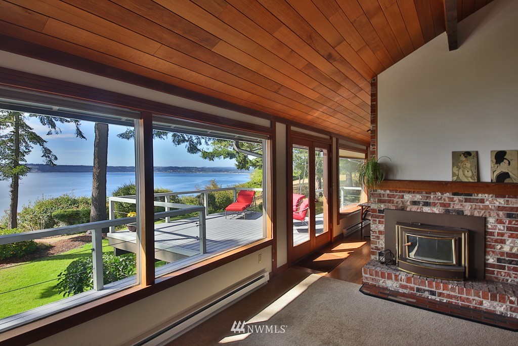 6924 Sills Road Clinton, WA 98236 - Photo 9 of 25 a living room with a fireplace and a floor to ceiling window