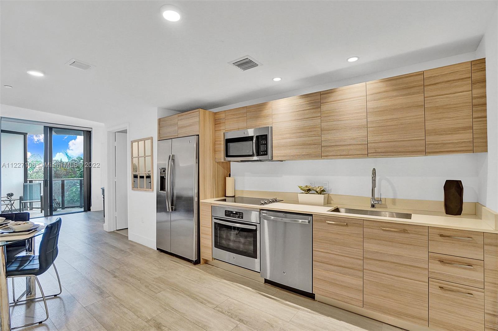a kitchen with a sink stainless steel appliances wooden floor and cabinets