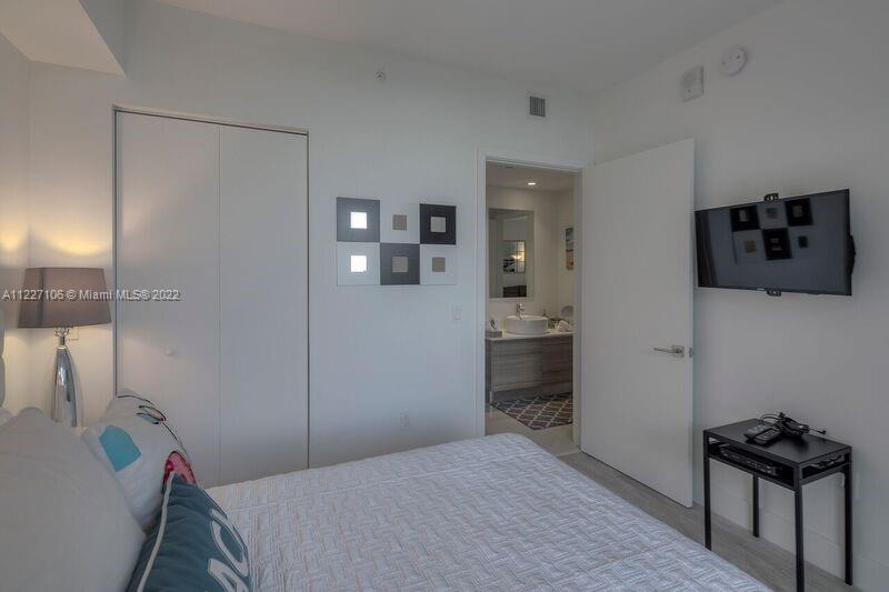 121 Northeast 34th Street, Unit 814 Miami, FL 33137 - Photo 20 of 38 a bedroom with a bed and a flat screen tv