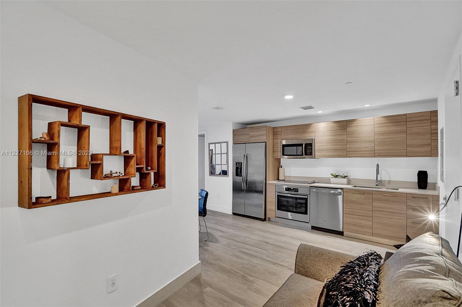 121 Northeast 34th Street, Unit 814 Miami, FL 33137 - Photo 25 of 38 a large white kitchen with stainless steel appliances granite countertop a stove and a sink