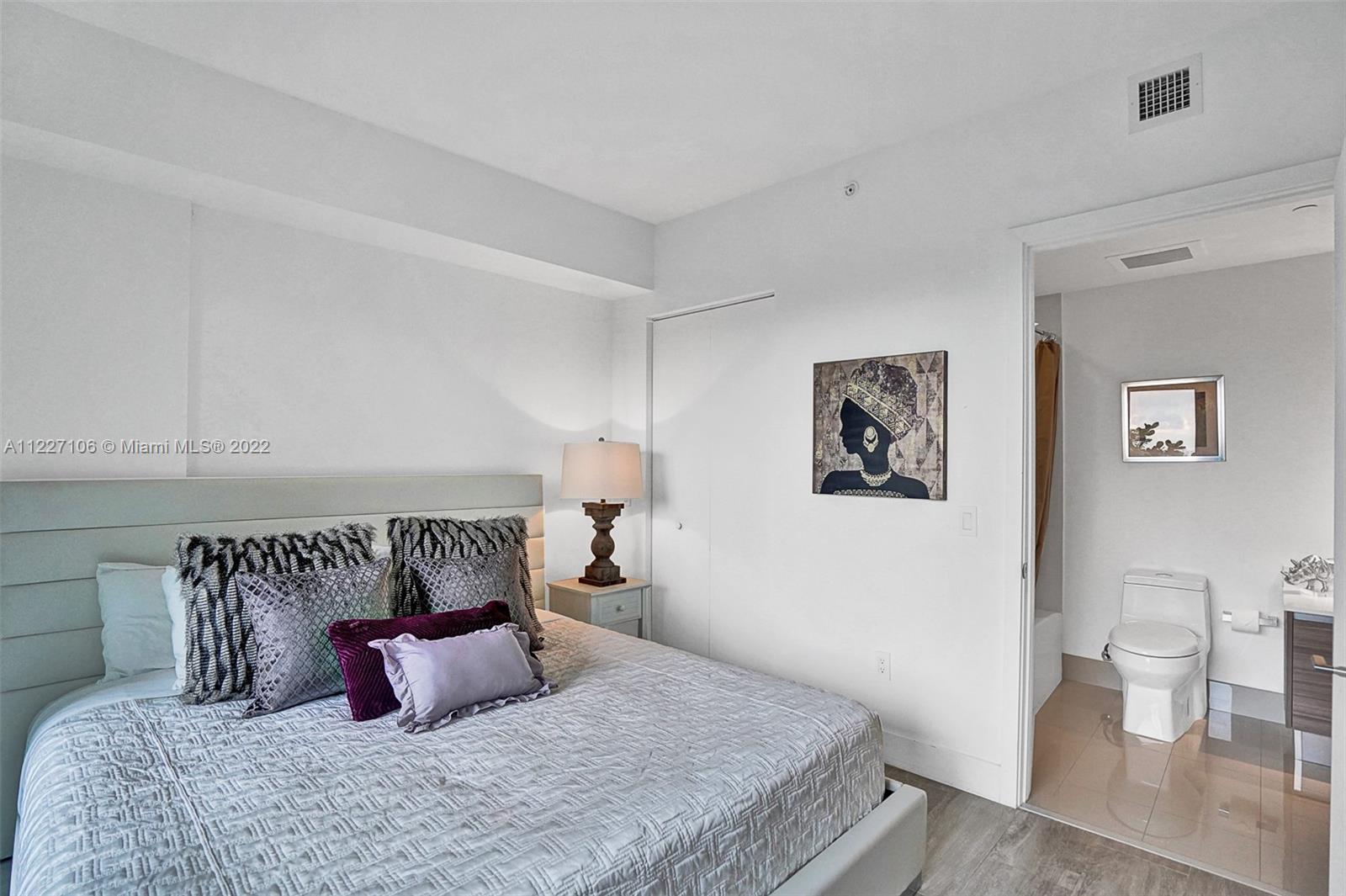 121 Northeast 34th Street, Unit 814 Miami, FL 33137 - Photo 37 of 38 a bedroom with a bed and painting on the wall