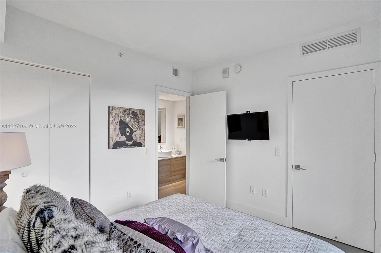 121 Northeast 34th Street, Unit 814 Miami, FL 33137 - Photo 38 of 38 a bedroom with a bed and a flat screen tv