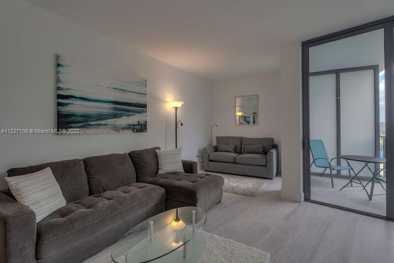 121 Northeast 34th Street, Unit 814 Miami, FL 33137 - Photo 9 of 38 a living room with furniture and a flat screen tv