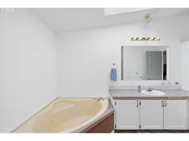 a bathroom with a sink vanity tub and a mirror