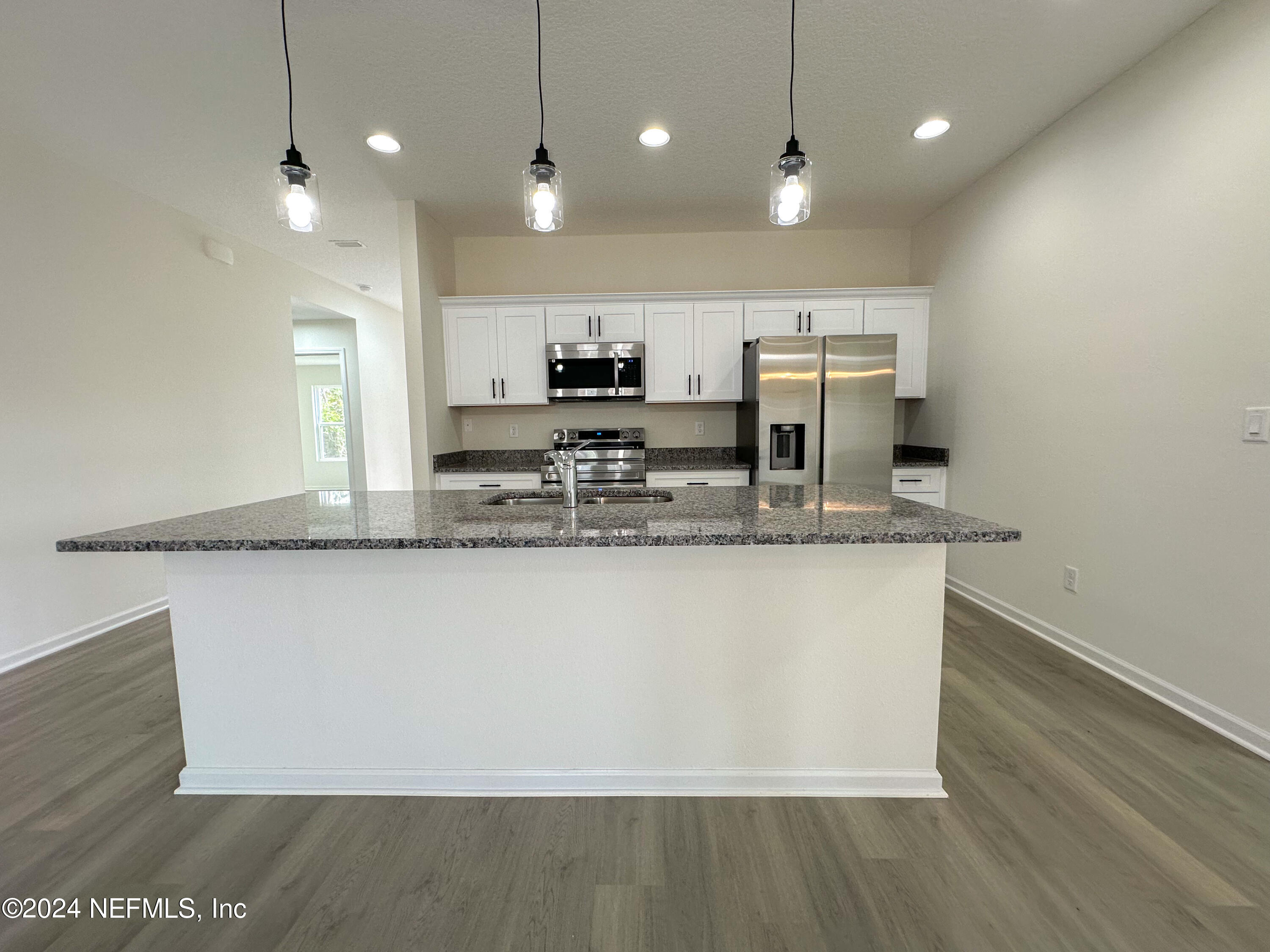1047 Fleming Street Fleming Island, FL 32003 - Photo 6 of 15 a large kitchen with kitchen island a stove a sink a refrigerator and a microwave