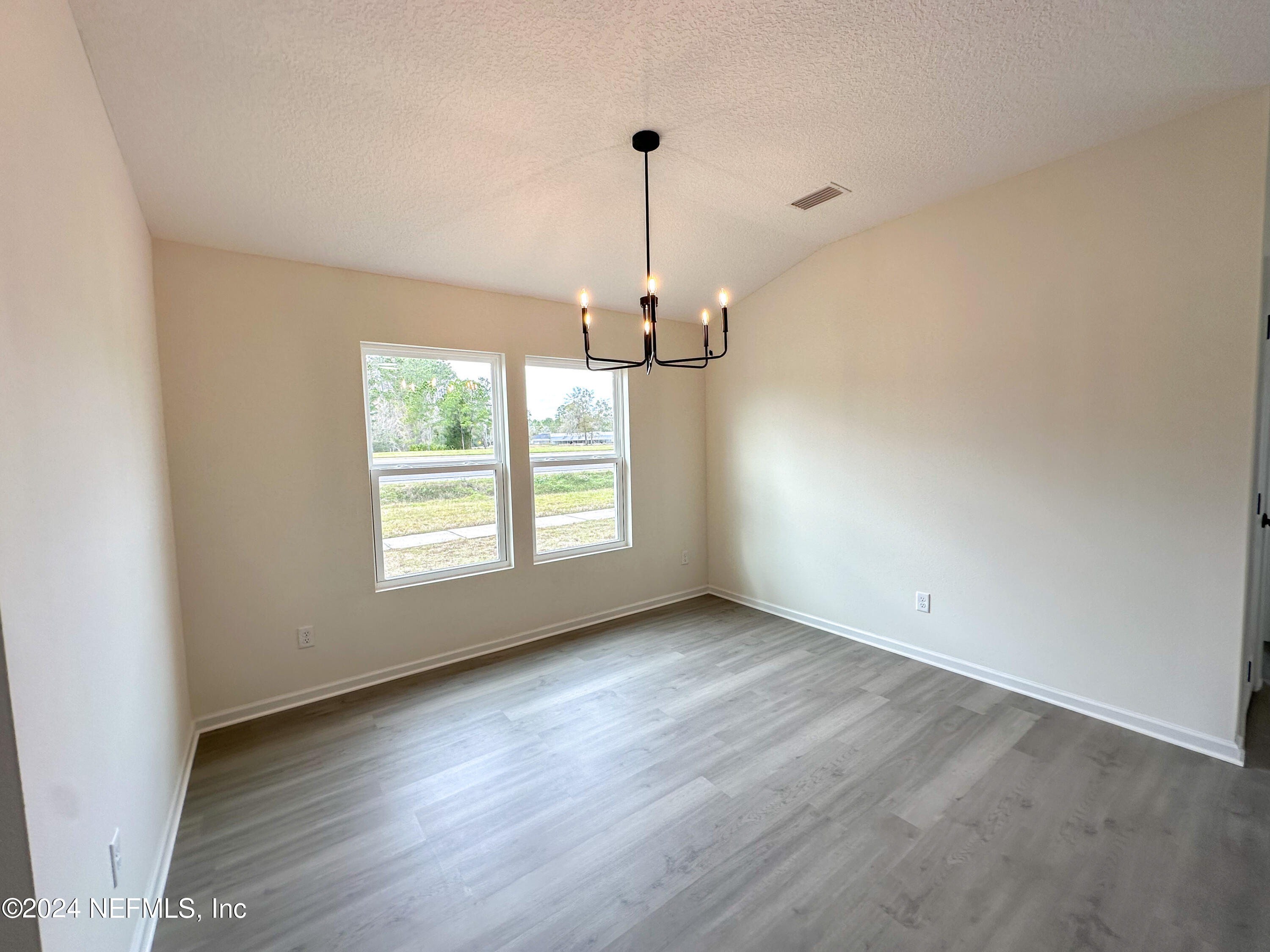 1047 Fleming Street Fleming Island, FL 32003 - Photo 8 of 15 an empty room with wooden floor chandelier and windows