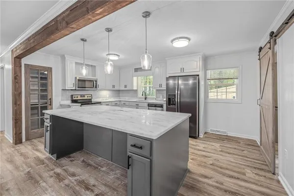 a kitchen with kitchen island a counter top space a sink appliances and cabinets