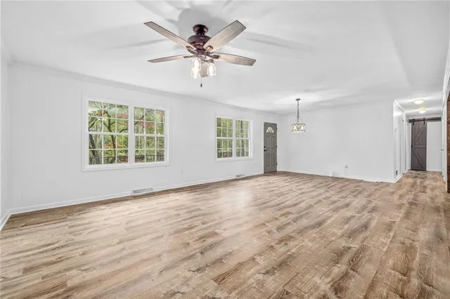 an empty room with wooden floor and a ceiling fan