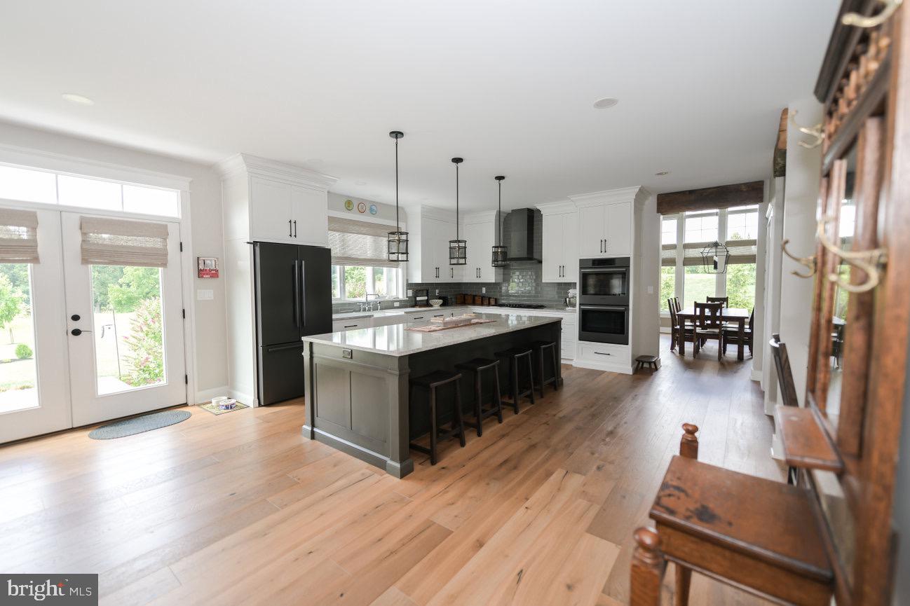 7091 Schoolhouse Road Hershey, PA 17033 - Photo 5 of 37 a open kitchen with stainless steel appliances granite countertop a stove top oven a refrigerator a dining table and chairs with wooden floor