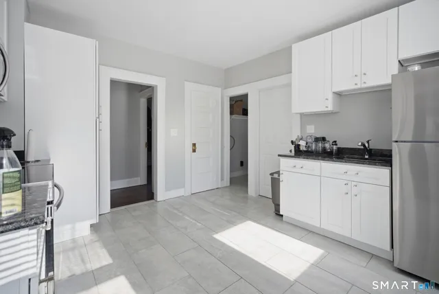 a kitchen with a refrigerator and white cabinets