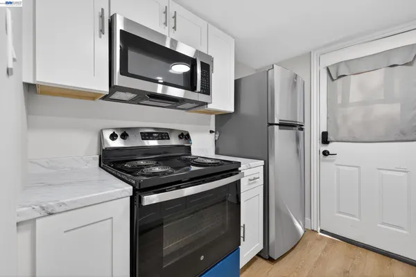 a kitchen with stainless steel appliances white cabinets and a stove top oven