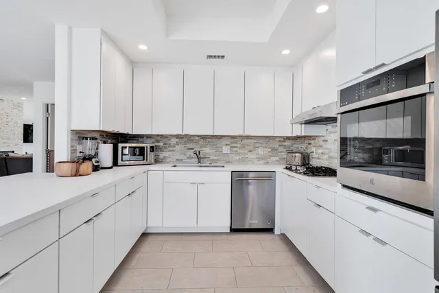 a kitchen with granite countertop white cabinets and white appliances