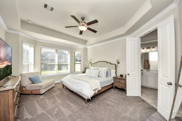 a bedroom with a bed a ceiling fan and a dresser