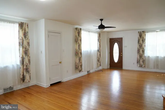 an empty room with wooden floor chandelier and windows