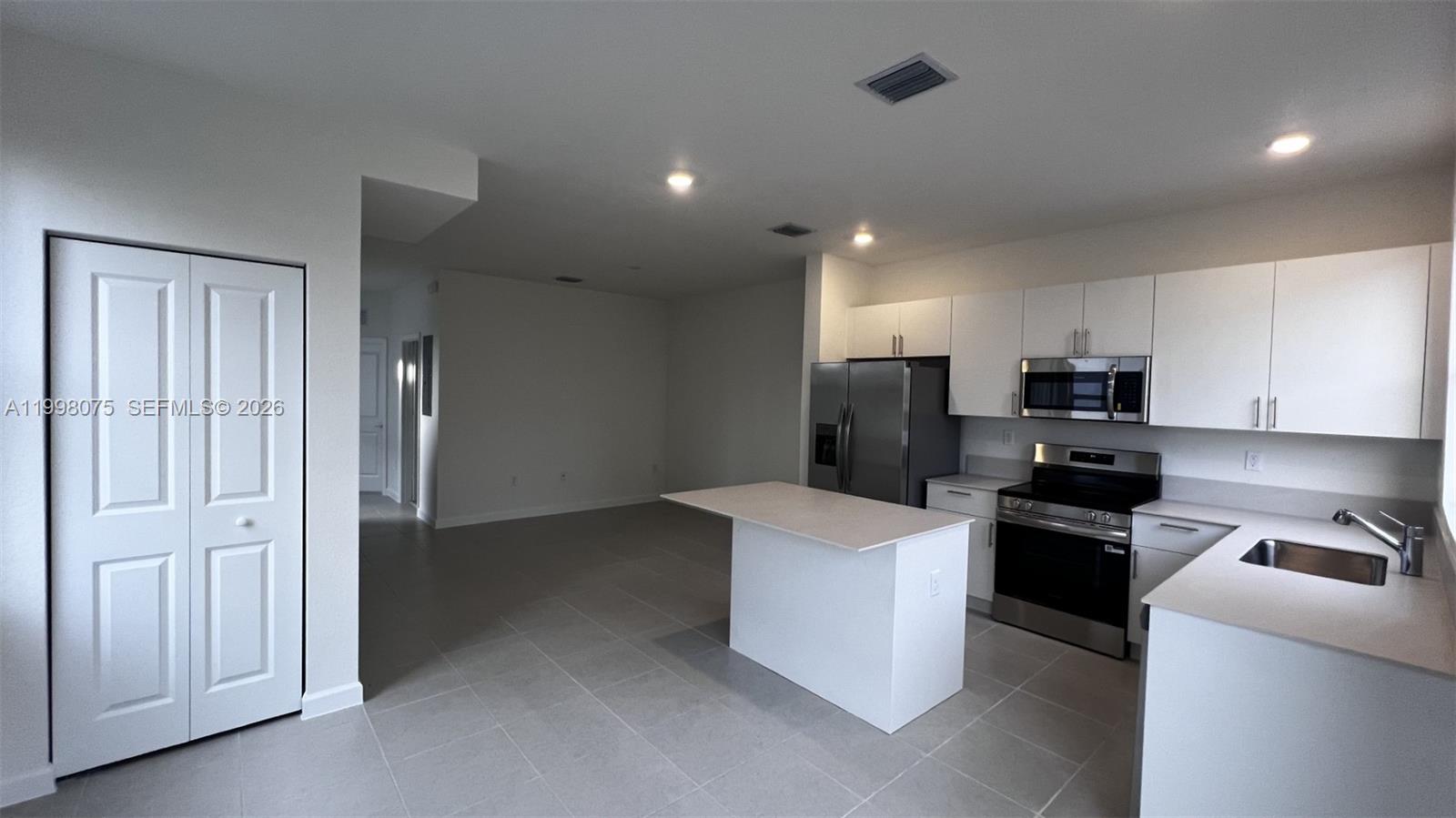15583 Southwest 277th Street, Unit 15583 Homestead, FL 33032 - Photo 10 of 27 a kitchen with stainless steel appliances kitchen island granite countertop a refrigerator oven a sink with dishwasher and white cabinets