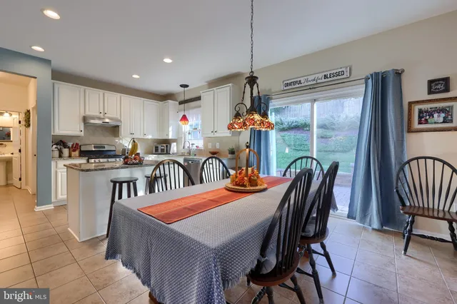 a kitchen with stainless steel appliances kitchen island granite countertop a table chairs and a refrigerator