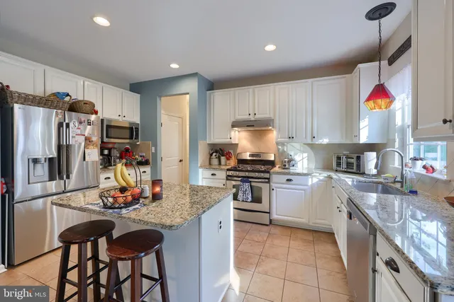 a kitchen with granite countertop a refrigerator stove top oven and sink