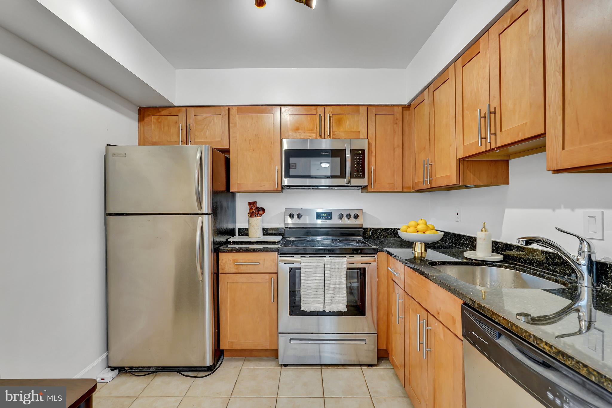 3401 38th Street Northwest, Unit 407 Washington, DC 20016 - Photo 14 of 37 a kitchen with granite countertop a refrigerator stove top oven a sink and dishwasher