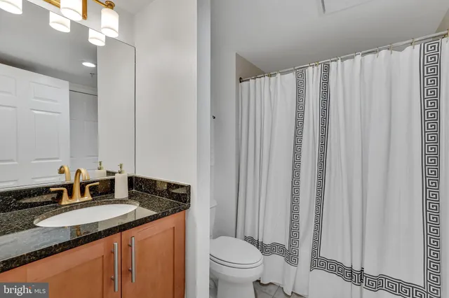 a bathroom with a granite countertop sink and a mirror with toilet