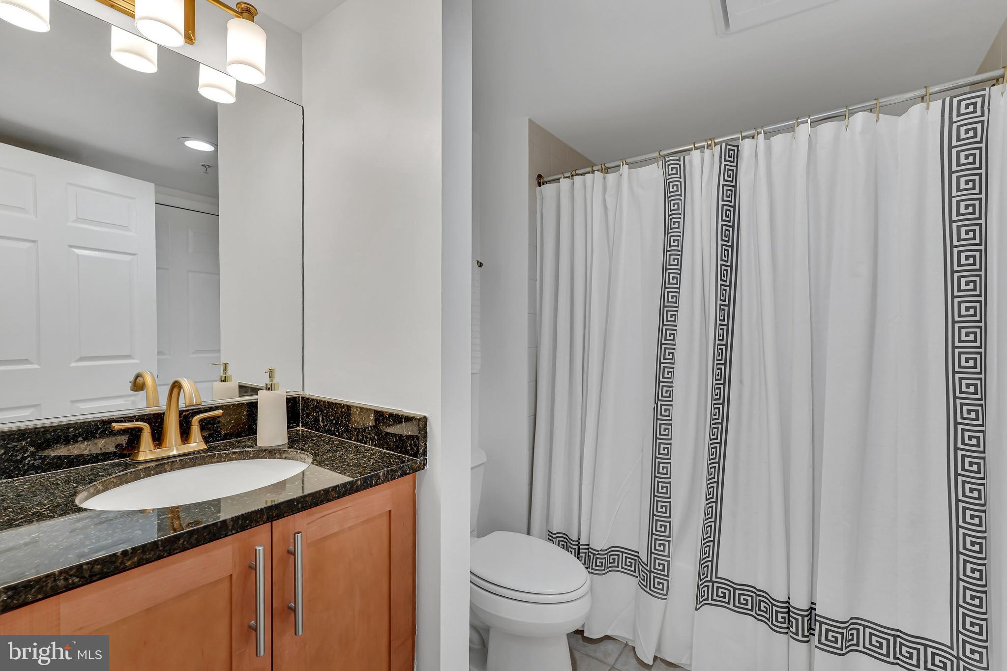 3401 38th Street Northwest, Unit 407 Washington, DC 20016 - Photo 26 of 37 a bathroom with a granite countertop sink and a mirror with toilet