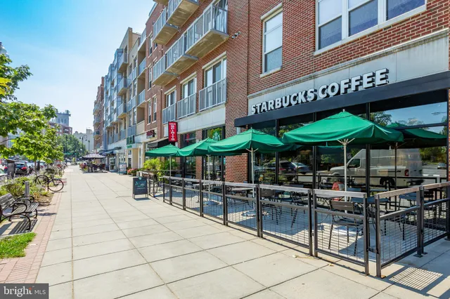 a view of a cafe with a couple of people seating in front of a building