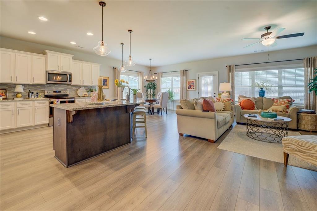616 Haven Way Monroe, GA 30655 - Photo 5 of 40 a living room with stainless steel appliances kitchen island granite countertop a stove a sink a refrigerator and white cabinets with wooden floor