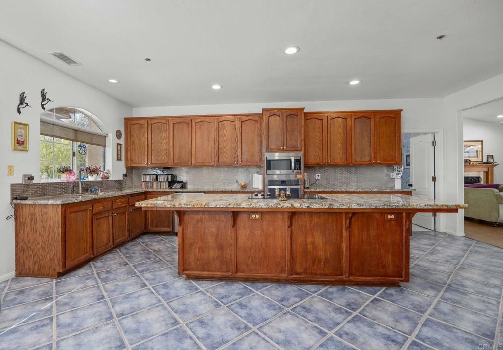7635 Little Creek Road San Marcos, CA 92078 - Photo 11 of 48 a kitchen with stainless steel appliances granite countertop a stove a sink a microwave a counter top space and cabinets