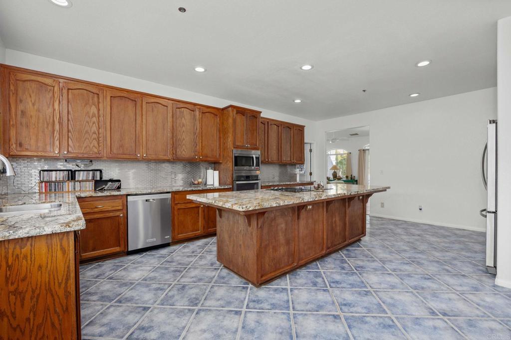 7635 Little Creek Road San Marcos, CA 92078 - Photo 10 of 48 a kitchen with stainless steel appliances granite countertop a stove top oven a sink a counter top space and cabinets