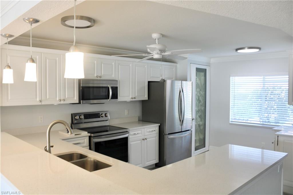 a kitchen with stainless steel appliances granite countertop a sink a stove a refrigerator cabinets a dining table and chairs