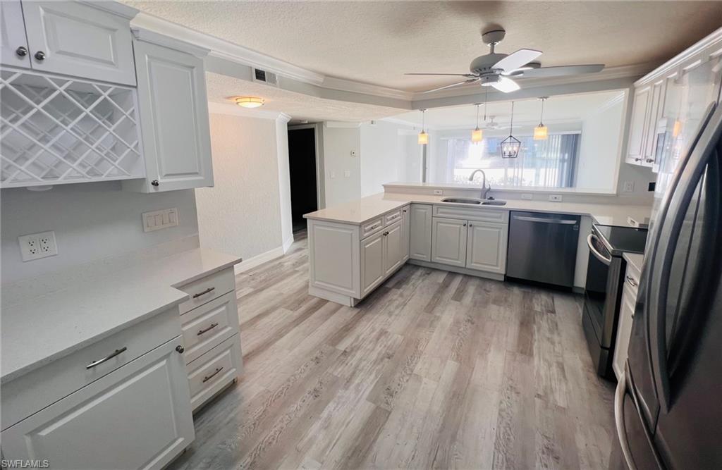 409 Gabriel Circle, Unit 2203 Naples, FL 34104 - Photo 3 of 18 a large kitchen with a wooden floor and stainless steel appliances