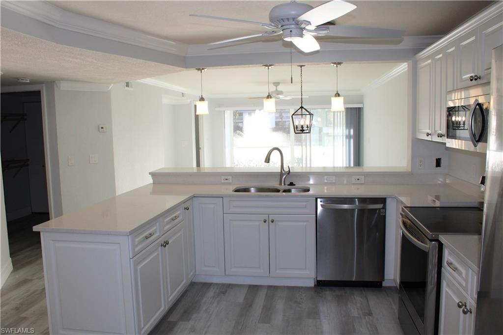 409 Gabriel Circle, Unit 2203 Naples, FL 34104 - Photo 5 of 18 a kitchen with a sink dishwasher a stove and a refrigerator with wooden floor