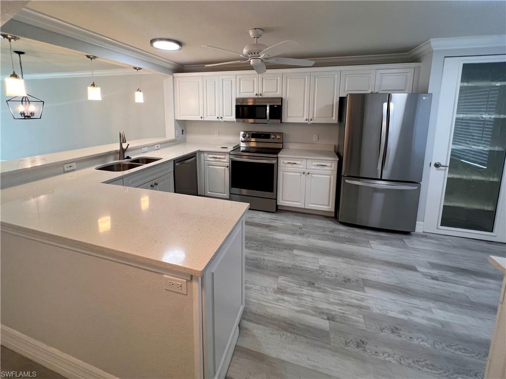 409 Gabriel Circle, Unit 2203 Naples, FL 34104 - Photo 6 of 18 a kitchen with a sink a microwave a refrigerator and stainless steel appliances