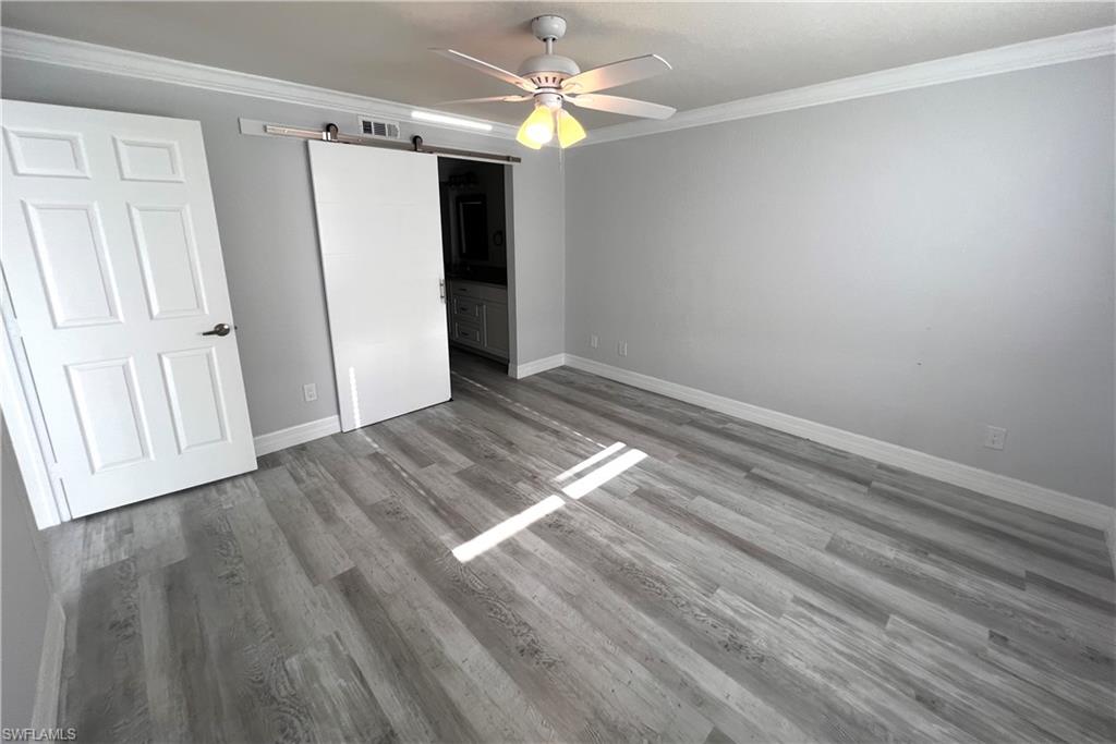 409 Gabriel Circle, Unit 2203 Naples, FL 34104 - Photo 9 of 18 wooden floor in an empty room with a window