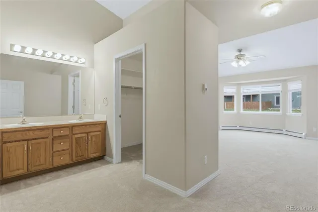 an empty room with chandelier fan and windows