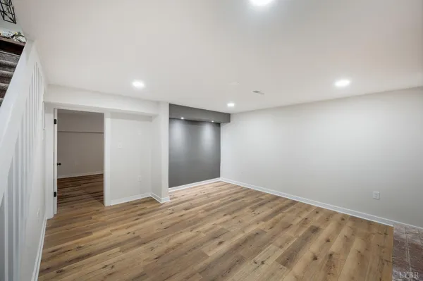 a view of an empty room with wooden floor fireplace and a window