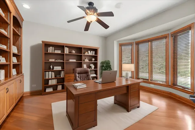 a view of empty room with wooden floor and fan